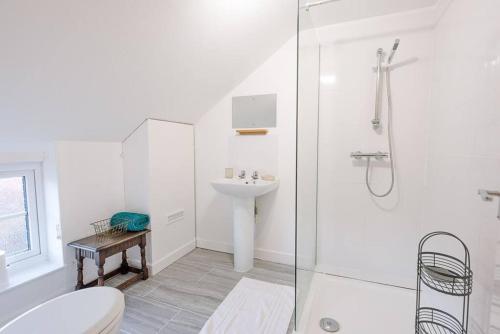 a white bathroom with a shower and a sink at Button Cottage in Wickham Market