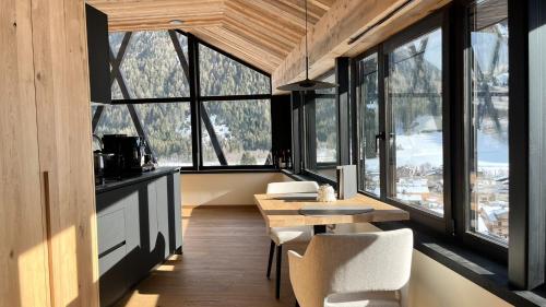 a room with a table and chairs and windows at Amus Suites Dolomites in Anterselva di Mezzo