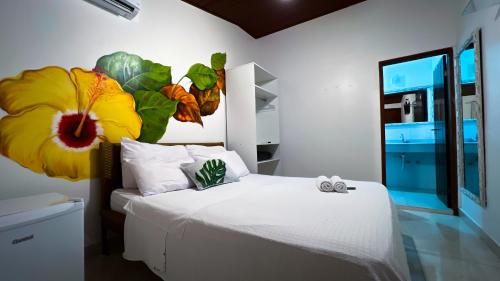 a bedroom with a bed with a large yellow flower on the wall at Pousada Praia e Conforto in Búzios