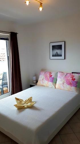 a white bed with a yellow bow on top of it at Apartmani Kalinic in Bijela
