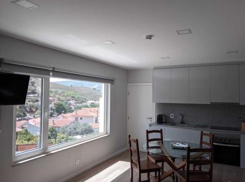 cocina con mesa, sillas y ventana en EiraDouro Casa Amendoeira, 