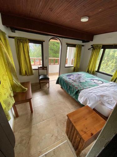 a bedroom with a bed and a chair and windows at Hacienda Buenos Aires en Iza in Iza