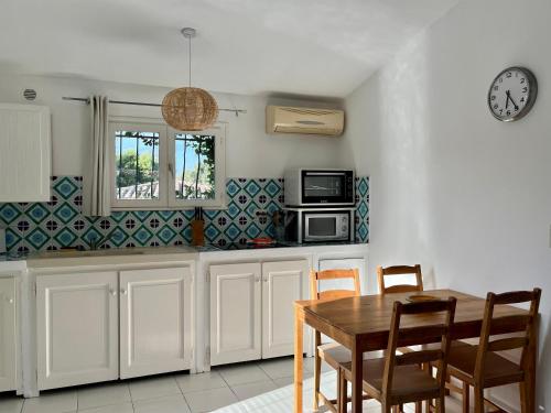 a kitchen with a table and a clock on the wall at Résidence Storia di Blue in Porto-Vecchio