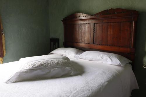 a bed with a wooden headboard and white pillows at Agriturismo Le Frise in Artogne