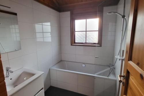een witte badkamer met een bad en een wastafel bij Wellness Bungalow Uppsala in Gramsbergen