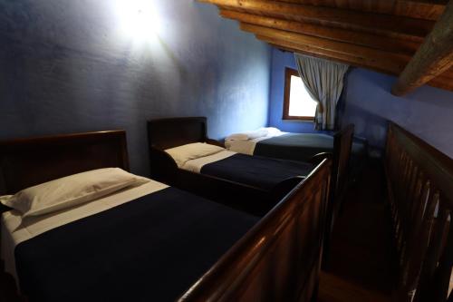 three beds in a room with blue walls and a window at Agriturismo Le Frise in Artogne