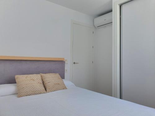 a bedroom with a white bed and a glass door at Apartamento nuevo en Primera Planta A con Piscina in Barbate