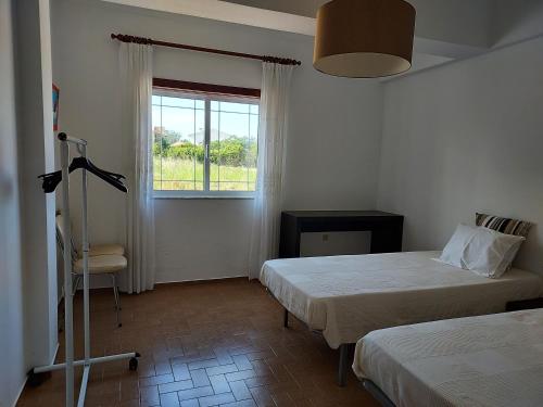 1 Schlafzimmer mit 2 Betten, einem Fenster und einem Stuhl in der Unterkunft Casa Férias 
