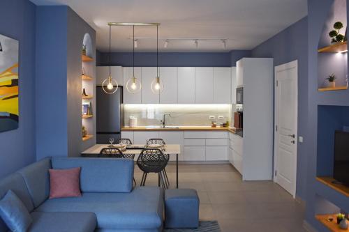 a living room and kitchen with blue walls and a blue couch at Vibrant Apartment in Tirana