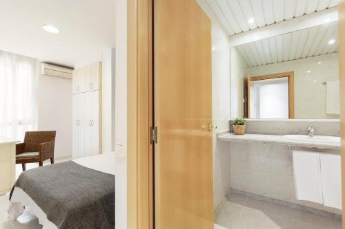 a bedroom with a bed and a bathroom with a sink at Andreas Apartments in Tarragona
