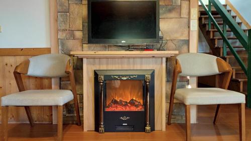 two chairs and a fireplace with a tv on top at Shiyai Taoyuan in Renai