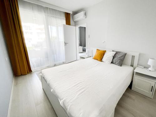biała sypialnia z dużym białym łóżkiem i oknem w obiekcie MyFlat Viewpoint 57 w Siófoku