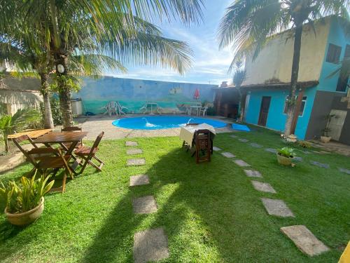 einen Hinterhof mit einem Tisch und einem Pool in der Unterkunft Casa de Praia Suítes in Saquarema