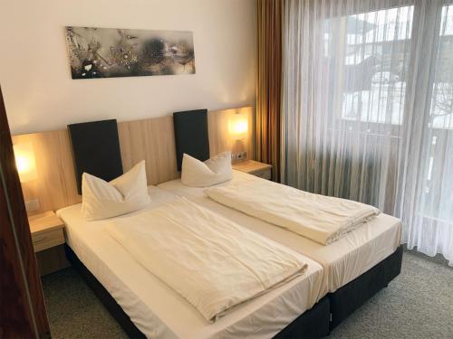 Schlafzimmer mit einem Bett mit weißer Bettwäsche und einem Fenster in der Unterkunft Chiemgau Appartements in Inzell