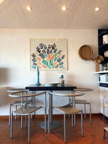 tavolo e sedie in una stanza con un dipinto sul muro di Marinella Sky View a Marinella