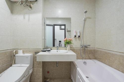 a bathroom with a sink and a tub and a toilet at Granda Quan Hoa Apartment in Hanoi