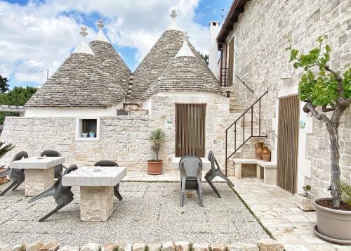 un patio avec des tables et des chaises et un bâtiment dans l'établissement Trulli Caroli, à Locorotondo