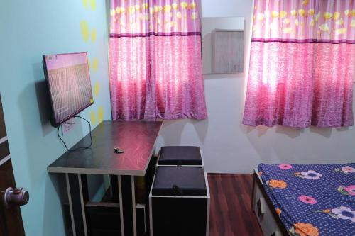 a room with a desk and pink curtains and a bed at OYO Galaxy Lodge in Partūr