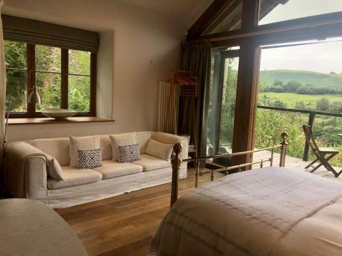 a living room with a couch and a large window at The Shippen - Open-plan barn conversion, high-spec, stunning views in Norbury