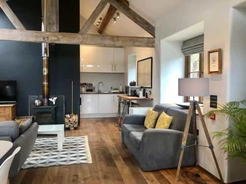a living room with a couch and a kitchen at The Shippen - Open-plan barn conversion, high-spec, stunning views in Norbury