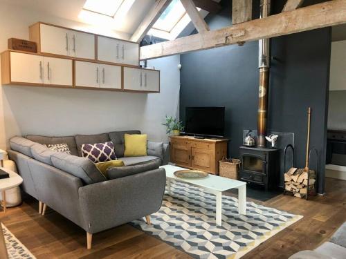 a living room with a couch and a table at The Shippen - Open-plan barn conversion, high-spec, stunning views in Norbury