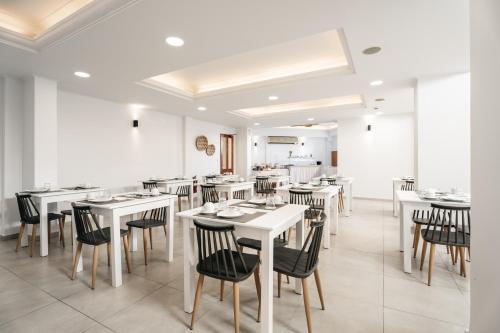 una sala da pranzo con tavoli bianchi e sedie nere di Petradi Beach Lounge Hotel a Rethymno