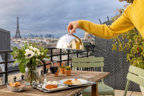 a woman standing on a balcony with a table with food at Le Littré in Paris