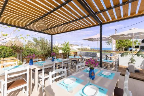 a restaurant with white tables and chairs and a view of the ocean at Banana Moon in Adelianos Kampos