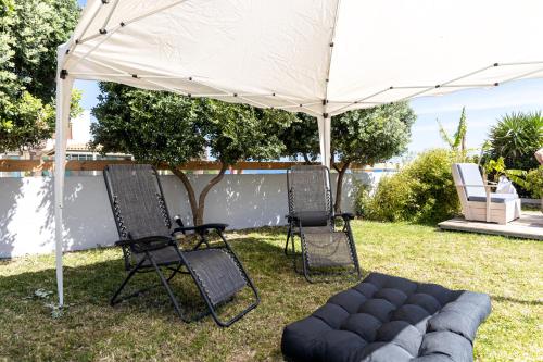 Biały parasol, dwa krzesła i kanapa pod nim. w obiekcie Banana Moon w Adelianos Kampos