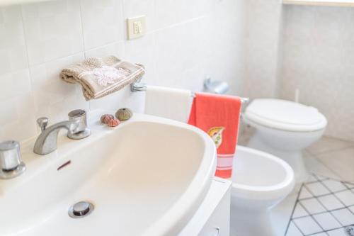 ein weißes Bad mit einem Waschbecken und einem WC in der Unterkunft Appartamento Levante PT - MyHo Casa in Torre Canne