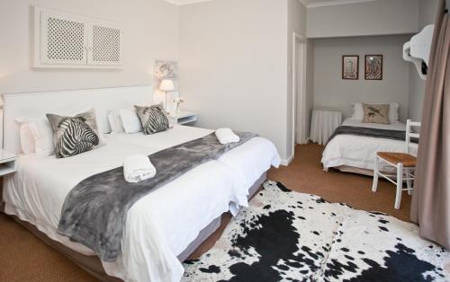 a bedroom with two beds and a table and a rug at Wagon Wheel Country Lodge in Beaufort West