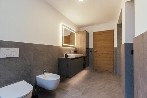 a bathroom with a white toilet and a sink at Alpenglow Apartments in Collalbo