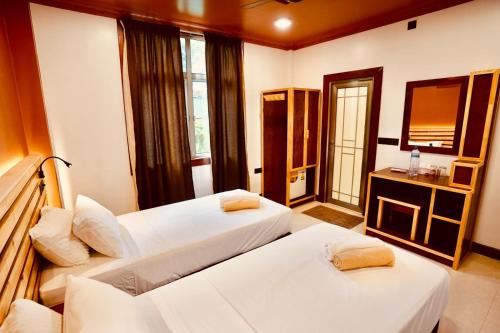 a hotel room with two beds and a television at Captal Island Villa in Mathiveri