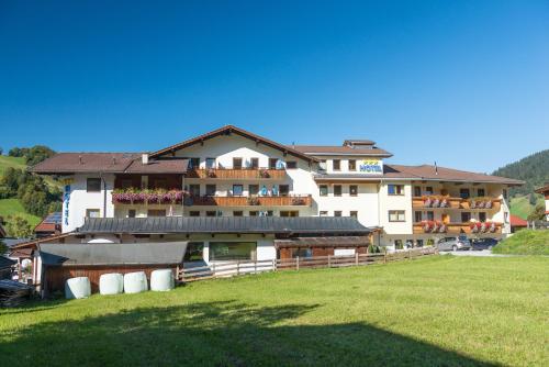 a large building with a green field in front of it at Hotel Schneeberger in Niederau