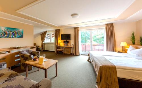 ein Hotelzimmer mit einem großen Bett und einem Tisch in der Unterkunft Thermenhotel Ströbinger Hof in Bad Endorf