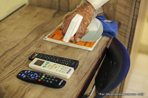 two remote controls and a person holding a bottle on a table at Flagship Green Palace in Patna