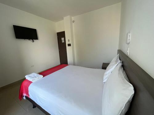a bedroom with a white bed and a flat screen tv at Mare S&M Casa Hostal in Manta
