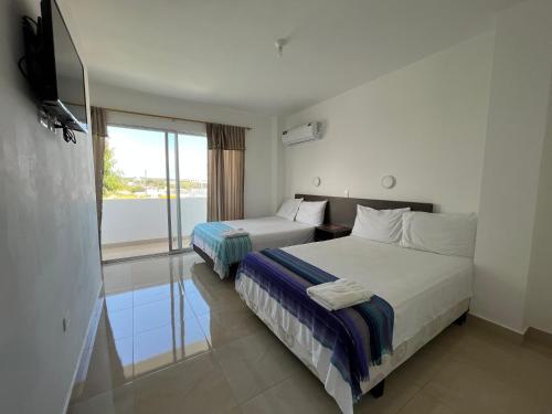 a hotel room with two beds and a balcony at Mare S&M Casa Hostal in Manta
