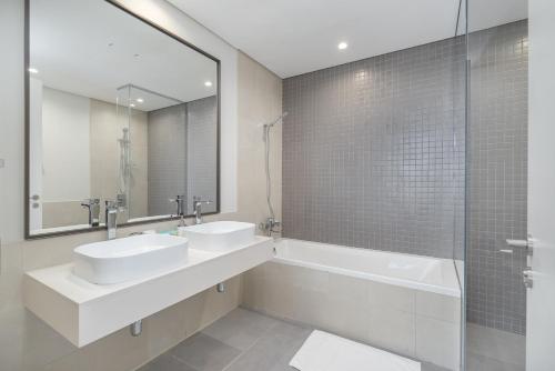 a bathroom with two sinks and a tub and a mirror at Upscale Two Bedroom with Balcony & Free Parking near Zabeel Park by Sojo Stay in Dubai