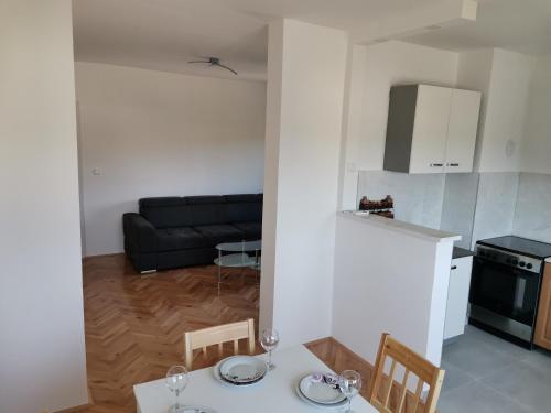 Bileća的住宿－AD Apartman Bileća，厨房以及带桌椅的起居室。