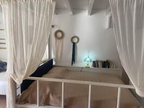 シミにあるSokratis Apartmentsのベッドルーム(白いカーテン付きの天蓋付きベッド1台付)