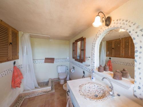 Un baño con lavabo, inodoro y espejo. en Sa Garriga de Can Barratot, en Selva