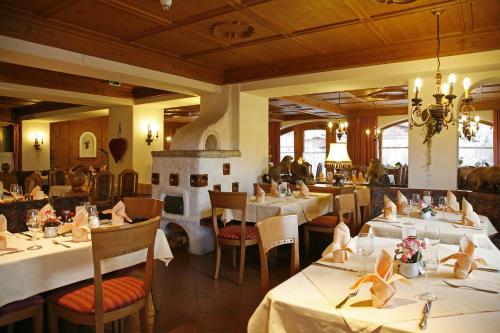 a restaurant with white tables and chairs and a room at Hotel Schneeberger in Niederau
