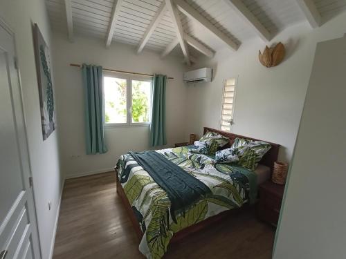 ein Schlafzimmer mit einem Bett und einem Fenster in der Unterkunft Villa 4 étoiles avec piscine, 3 chambres et jardin tropical in Saint-François