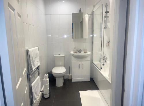 a white bathroom with a toilet and a sink at WATCH CHANGING OF THE GUARD AND WALK TO THE CASTLE! 2 Bedroom Apartment in Windsor