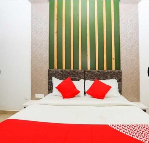 uma cama com duas almofadas vermelhas em cima em Flagship Sjr em Mysore
