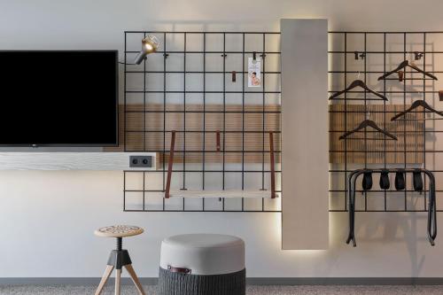 a room with a tv on a wall with a stool at Moxy Kaunas Center in Kaunas