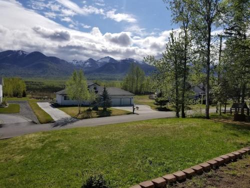 un patio con una casa y montañas al fondo en An upscale modern 4 bedroom 2 bath home with Mountain views en Anchorage