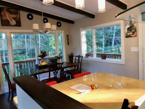 a dining room with a table and chairs and windows at Hot Tub Stunning Mountain Views 2 kitchens 4 bedroom 2 bathroom in Anchorage