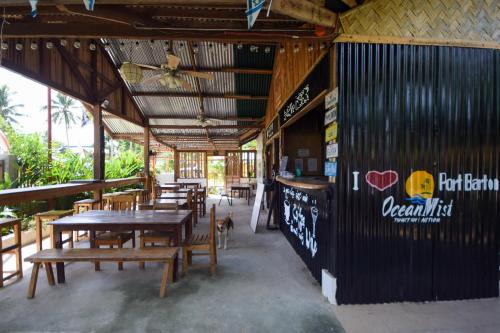 a restaurant with wooden tables and chairs and a bar at Ocean Mist Tourist Inn in San Vicente